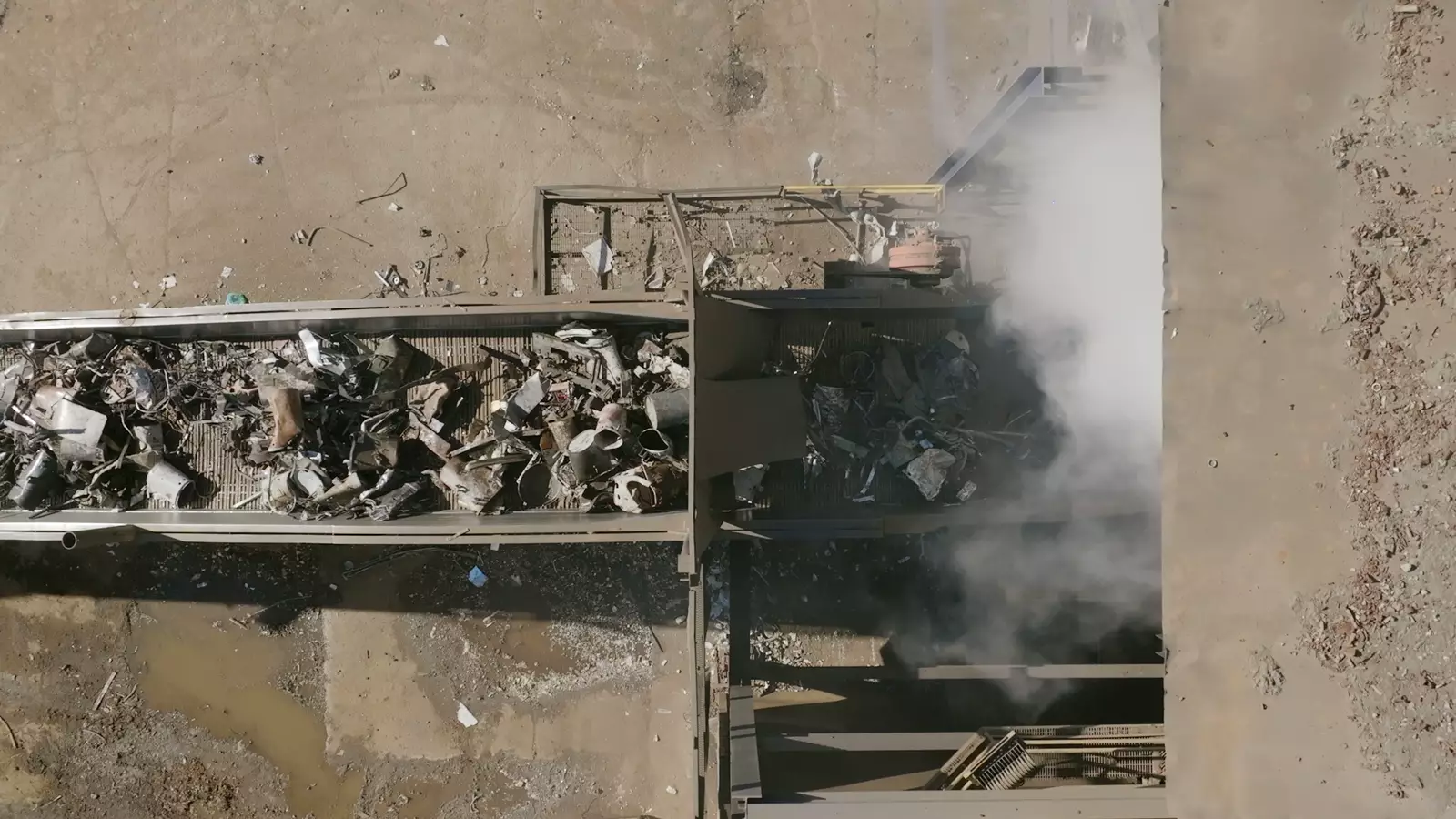 Conveyor belt of a recycling plant seen from above, loaded with scrap